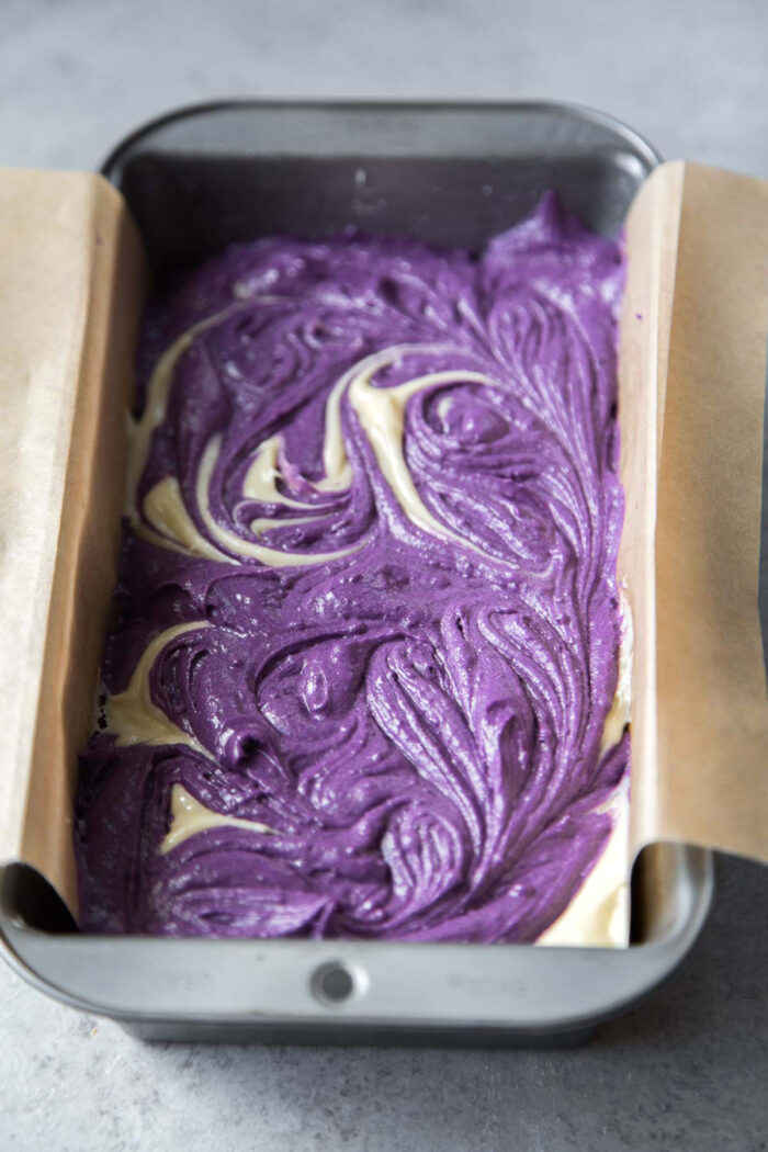 swirled marble ube pound cake in parchment paper lined loaf pan.