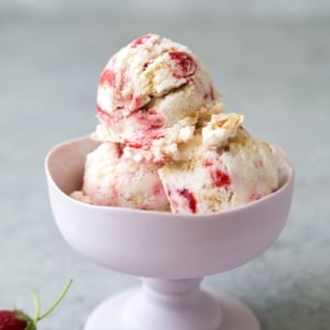 strawberry cheesecake ice cream scoops served in stemmed ice cream dish.