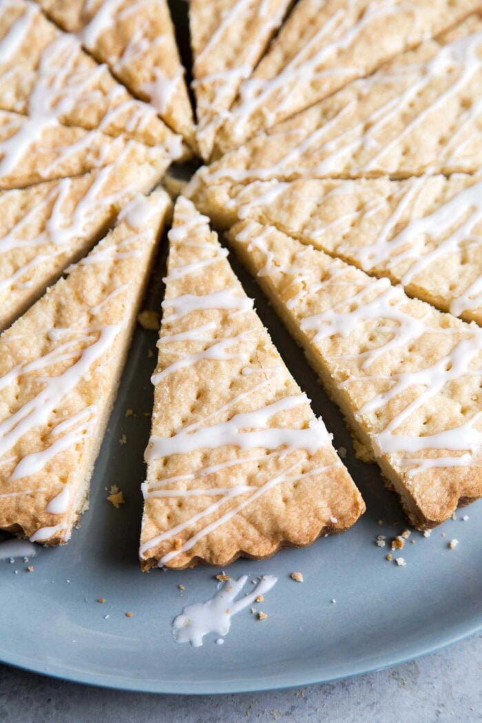 lemon shortbread cookie wedges topped with lemon glaze on blue plate.