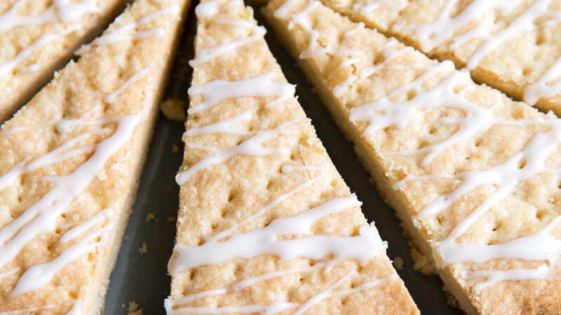 lemon shortbread cookie wedges topped with lemon glaze on blue plate.