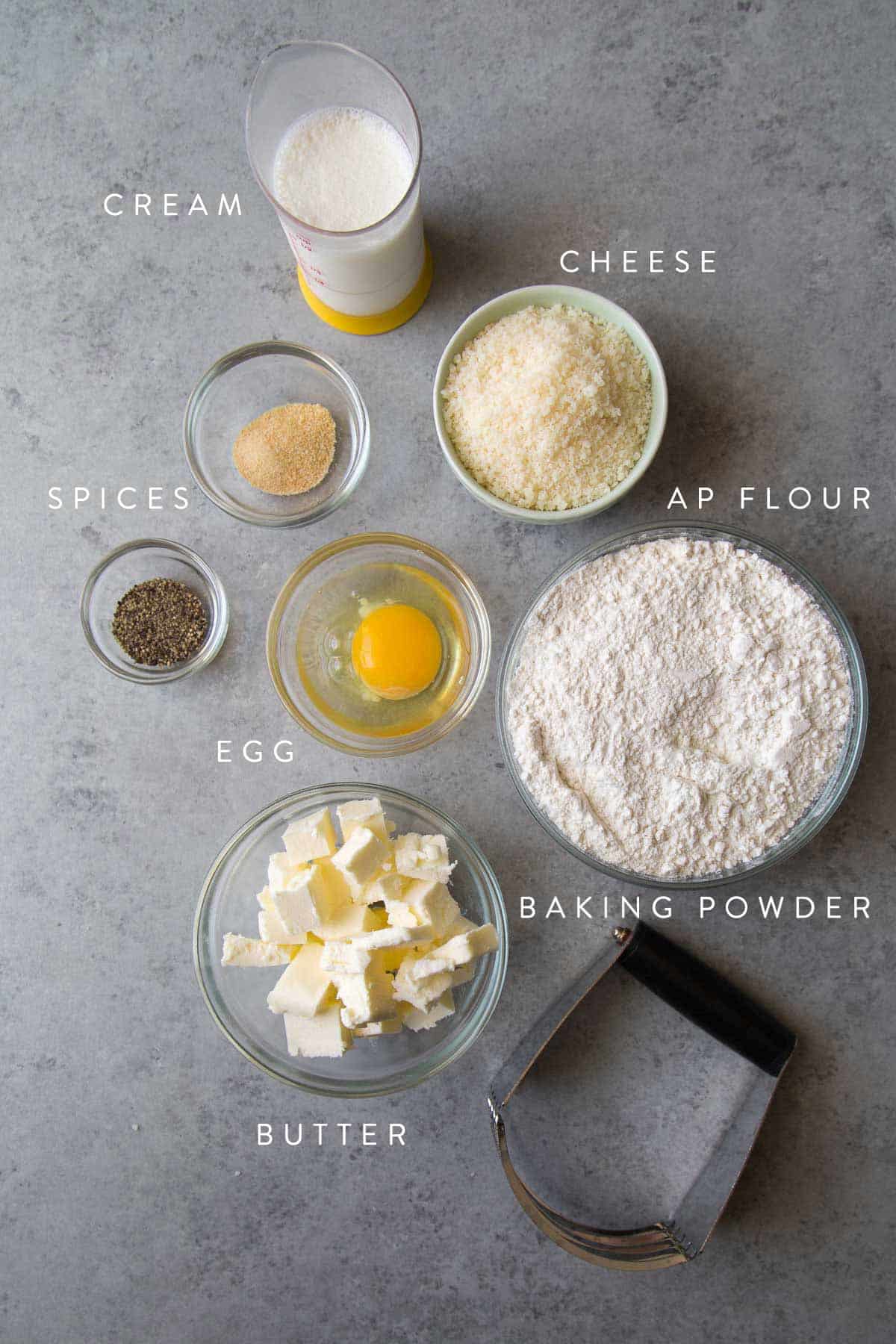 savory cheese scone ingredients laid out including all-purpose flour, butter, cream, and cheese.