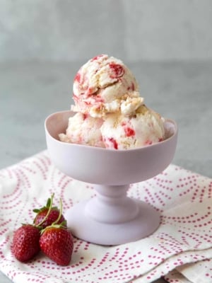 scoops of strawberry cheesecake ice cream in stemmed ice cream dish.