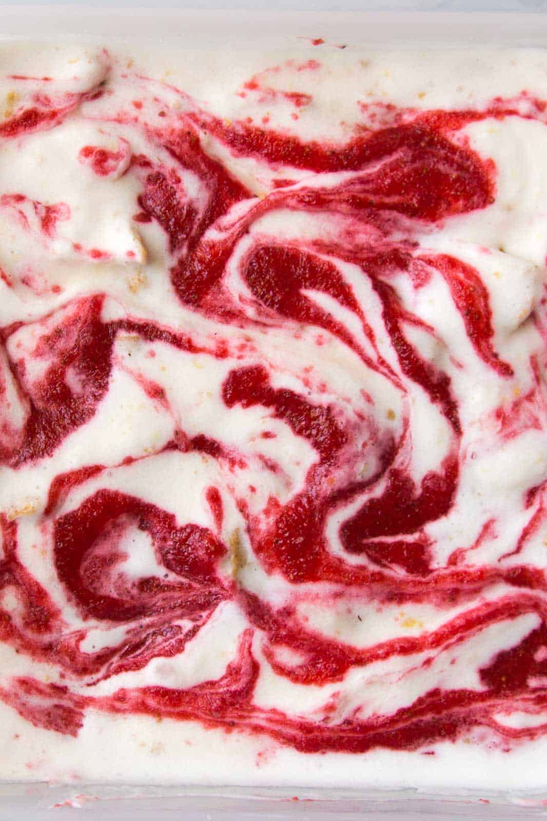 close up of strawberry swirled cheesecake ice cream with graham crackers chunks.