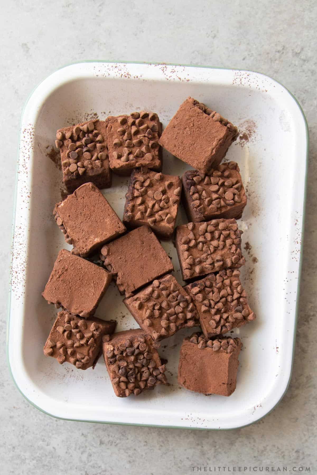 chocolate chip studded chocolate marshmallow squares arranged on white serving tray.