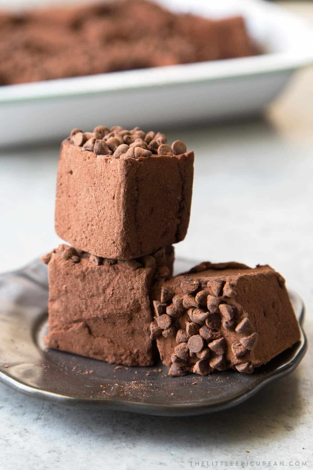 three pieces of chocolate chip chocolate marshmallow on dark serving plate.