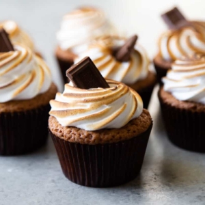 arranged s'mores cupcakes topped with toasted meringue frosting and garnished with chocolate bar.