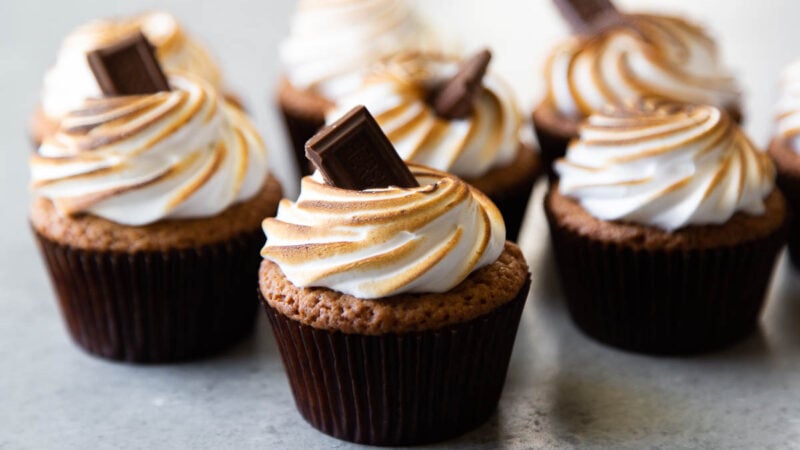 arranged s'mores cupcakes topped with toasted meringue frosting and garnished with chocolate bar.