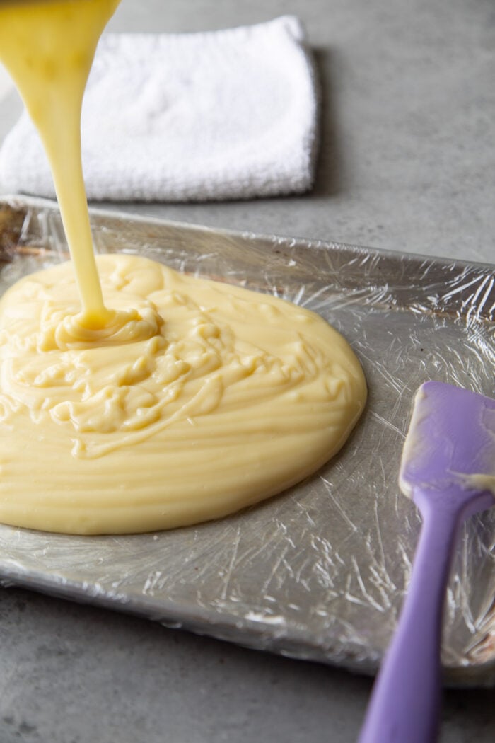 pour hot pastry cream into plastic wrapped baking sheet.