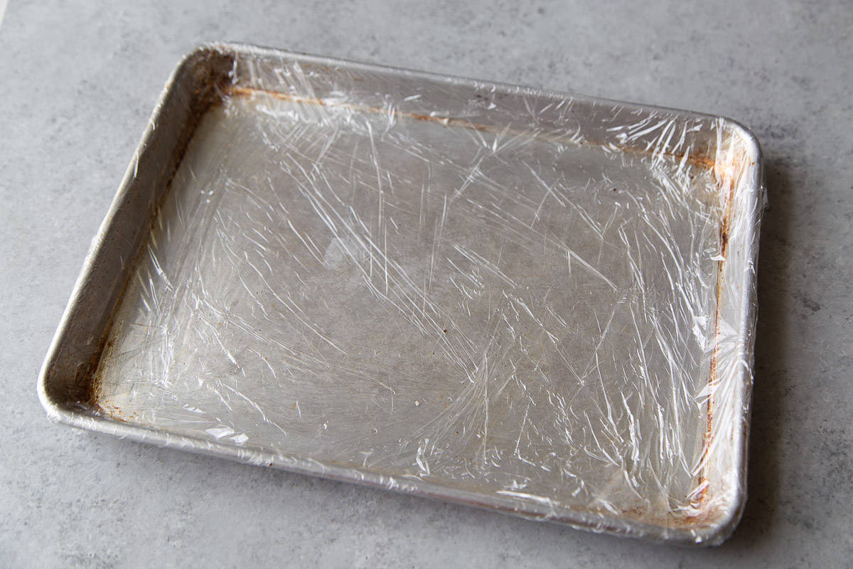 plastic wrapped and lined baking sheet ready for pastry cream.