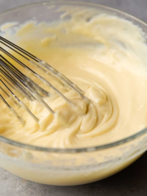 pastry cream in glass mixing bowl with balloon whisk.