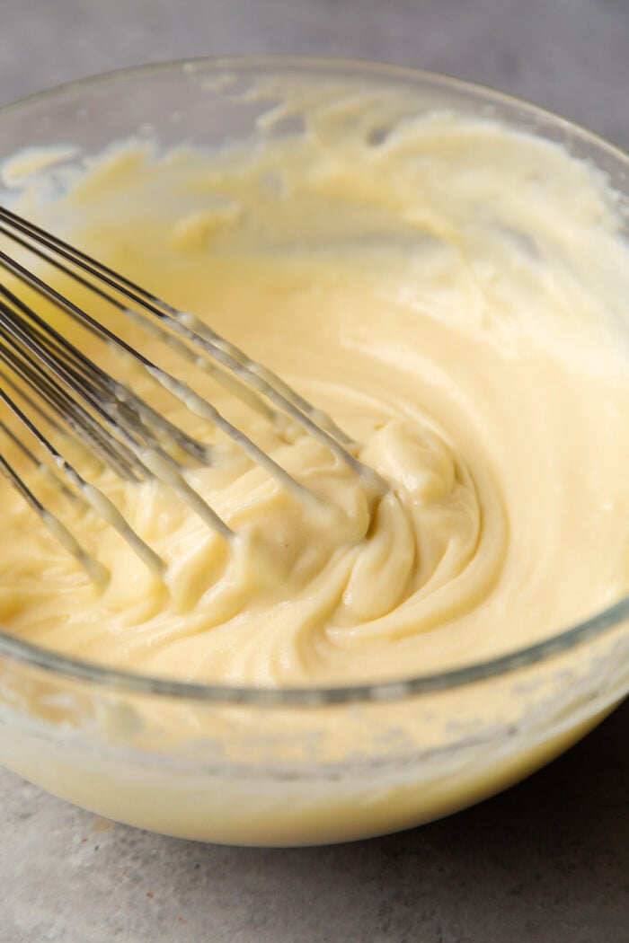pastry cream in glass mixing bowl with balloon whisk.