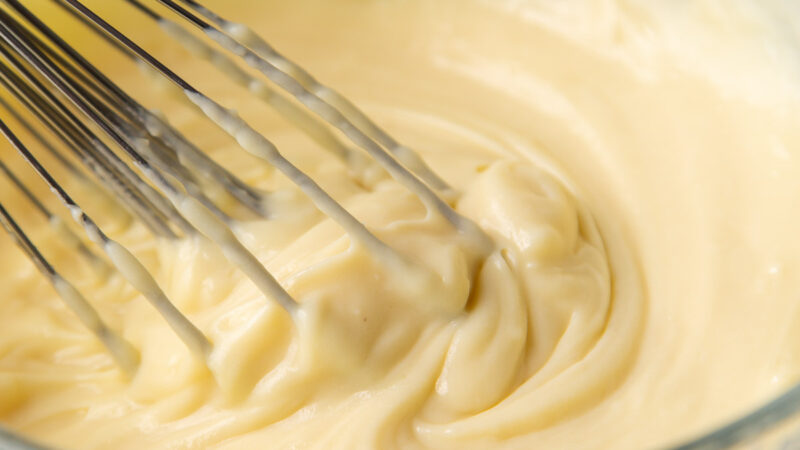 pastry cream in glass mixing bowl with balloon whisk.