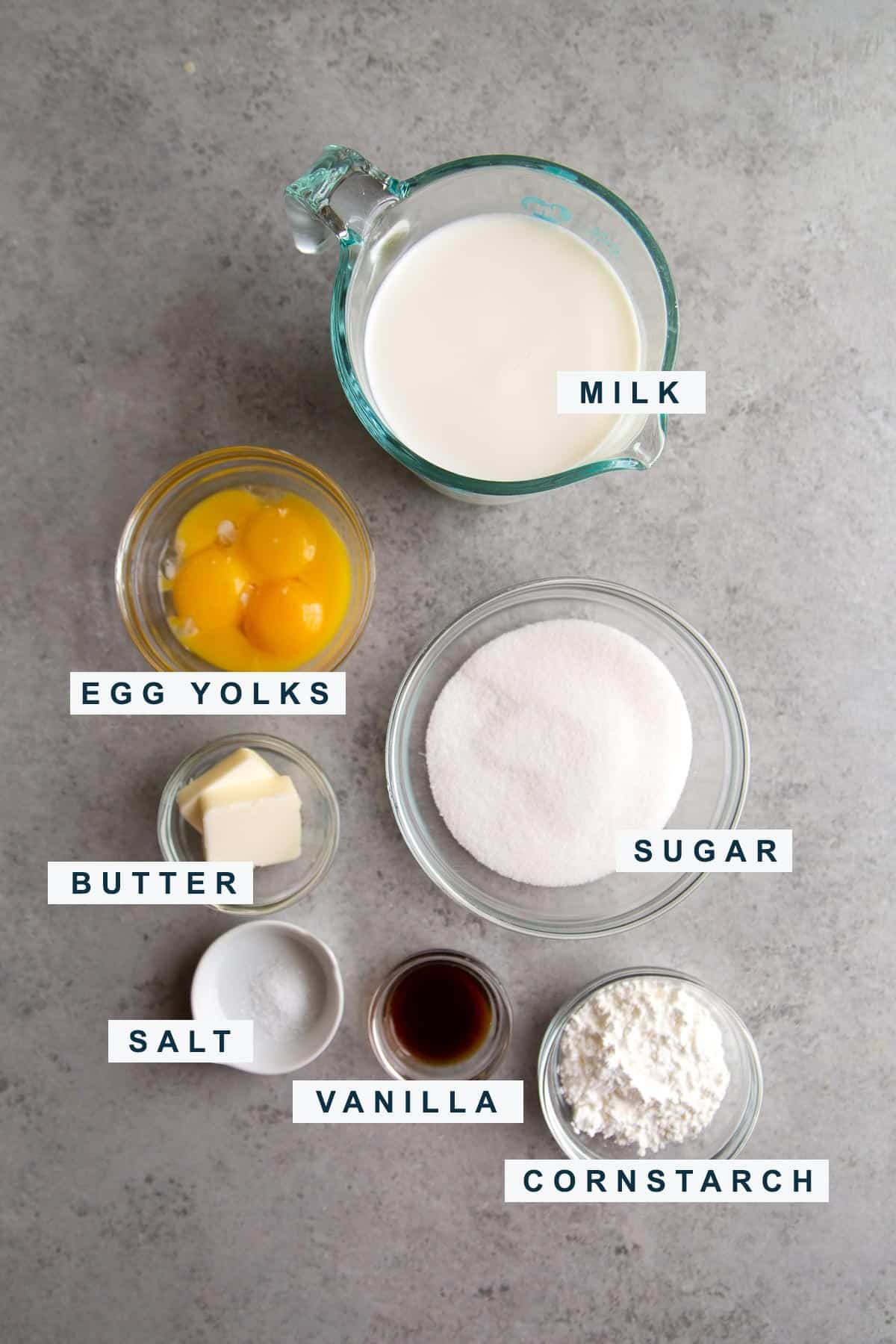 portioned out ingredients needed to make pastry cream include milk, egg yolks, cornstarch, and sugar.