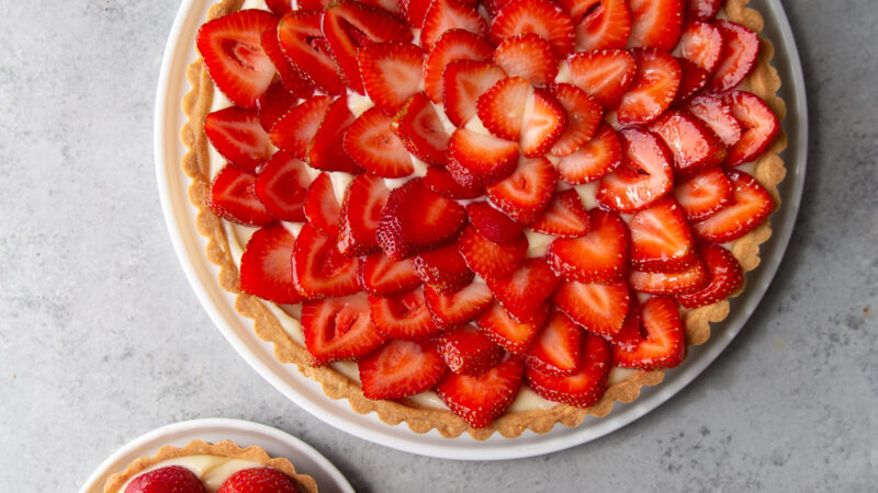 two versions of strawberry tart featuring one with whole strawberries and one with sliced strawberries.