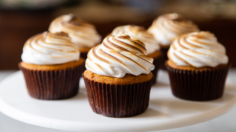 six sweet potato cupcakes with toasted marshmallow meringue frosting on cake stand.