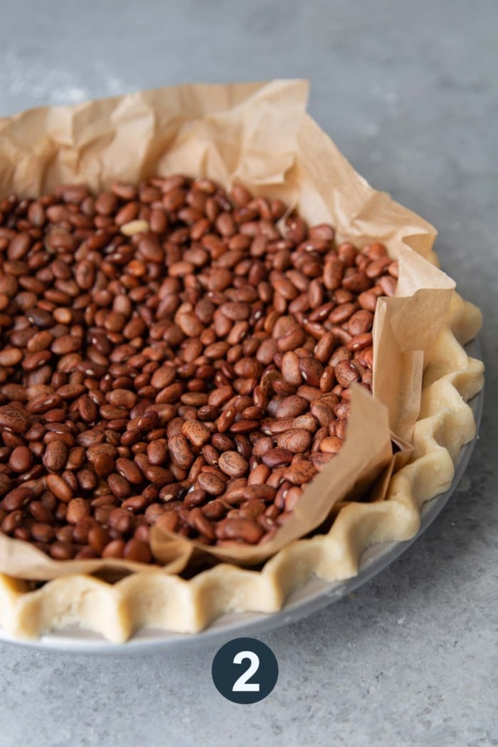 pie dough lined with parchment paper and baking bean for blind bake.