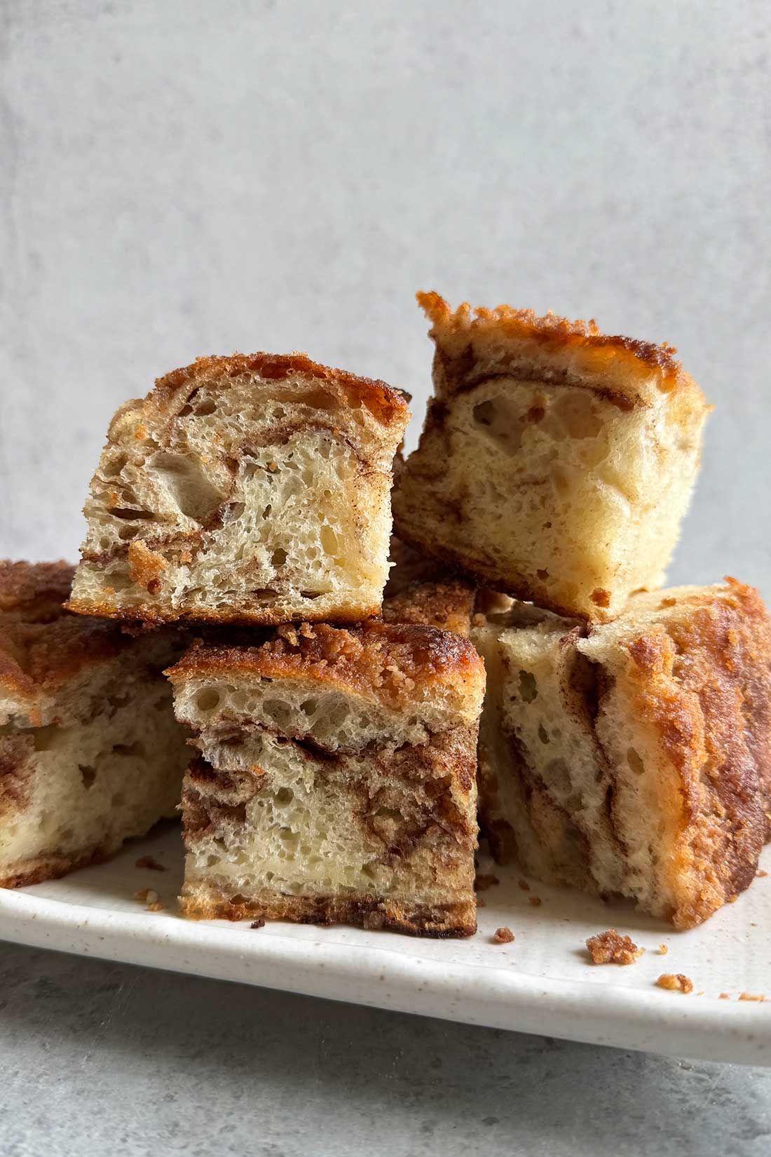 pieces of cinnamon focaccia bread stacked on a white plate.