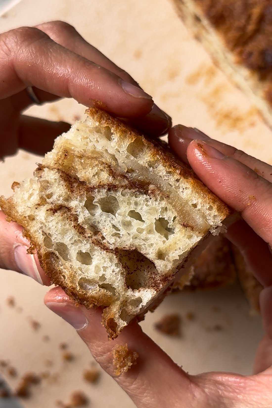 hands holding soft fluffy sweet cinnamon focaccia bread.
