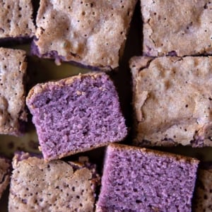 scattered portions of ube cake brownies on parchment paper.