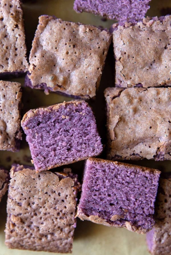 scattered portions of ube cake brownies on parchment paper.