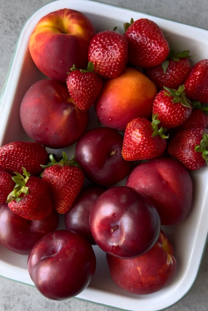 serving platter filled with california nectarines, strawberries and plums.