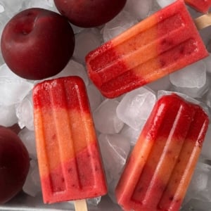layered summer fruit popsicles on ice lined sheet tray.