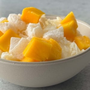 fresh mango chunks, mochi pieces, and shaved ice in bowl.