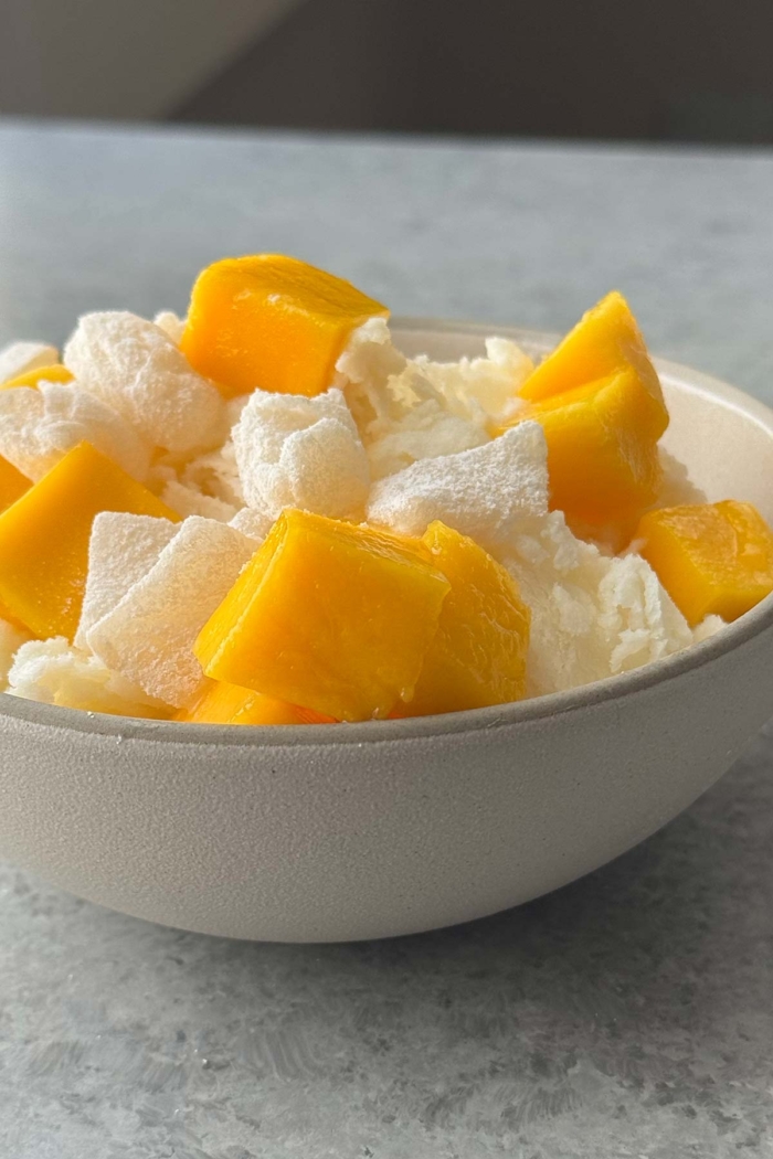 fresh mango chunks, mochi pieces, and shaved ice in bowl.