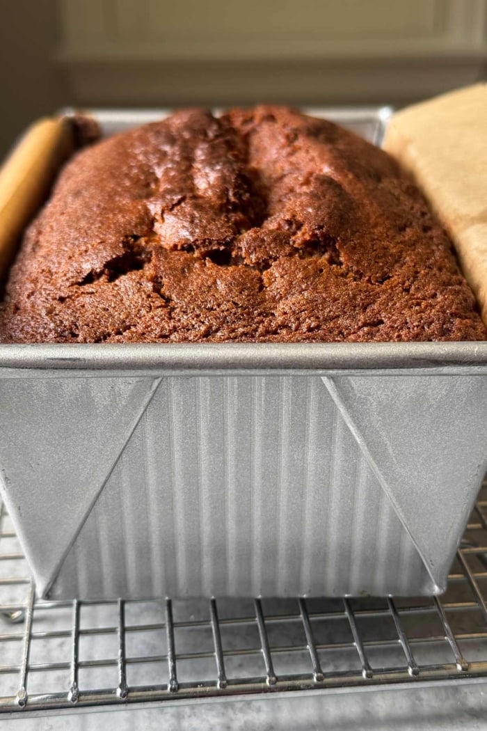 mochi banana bread in loaf pan on wire rack.