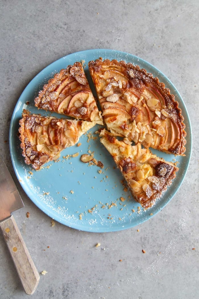 portioned out slices of apple frangipane tart on blue serving plate.