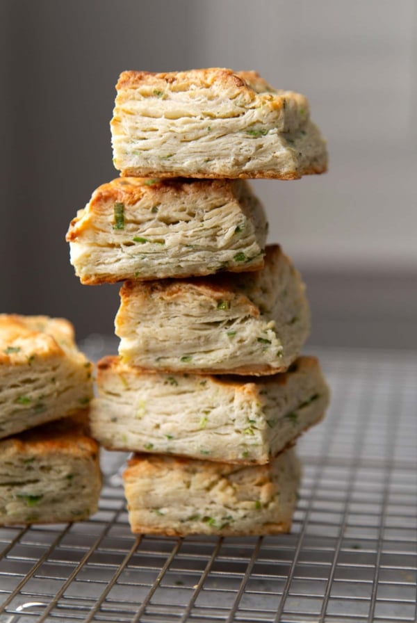five ranch scallion biscuits stacked on top of each other on wire rack.