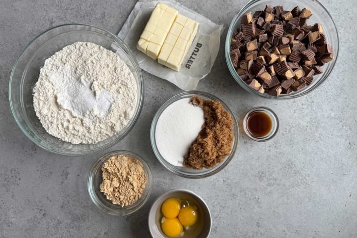 overhead portioned out ingredients for thick cookies filled with chocolate chunks and chopped Reese's peanut butter cups.