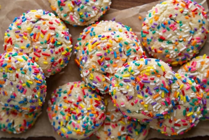 several rainbow confetti cookies randomly arranged on parchment paper.