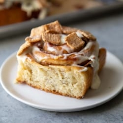close up on cinnamon roll on white serving plate.