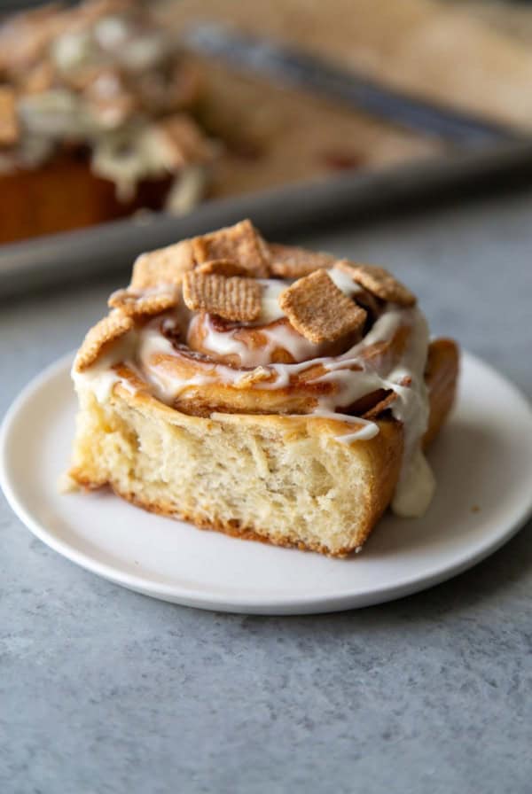 close up on cinnamon roll on white serving plate.
