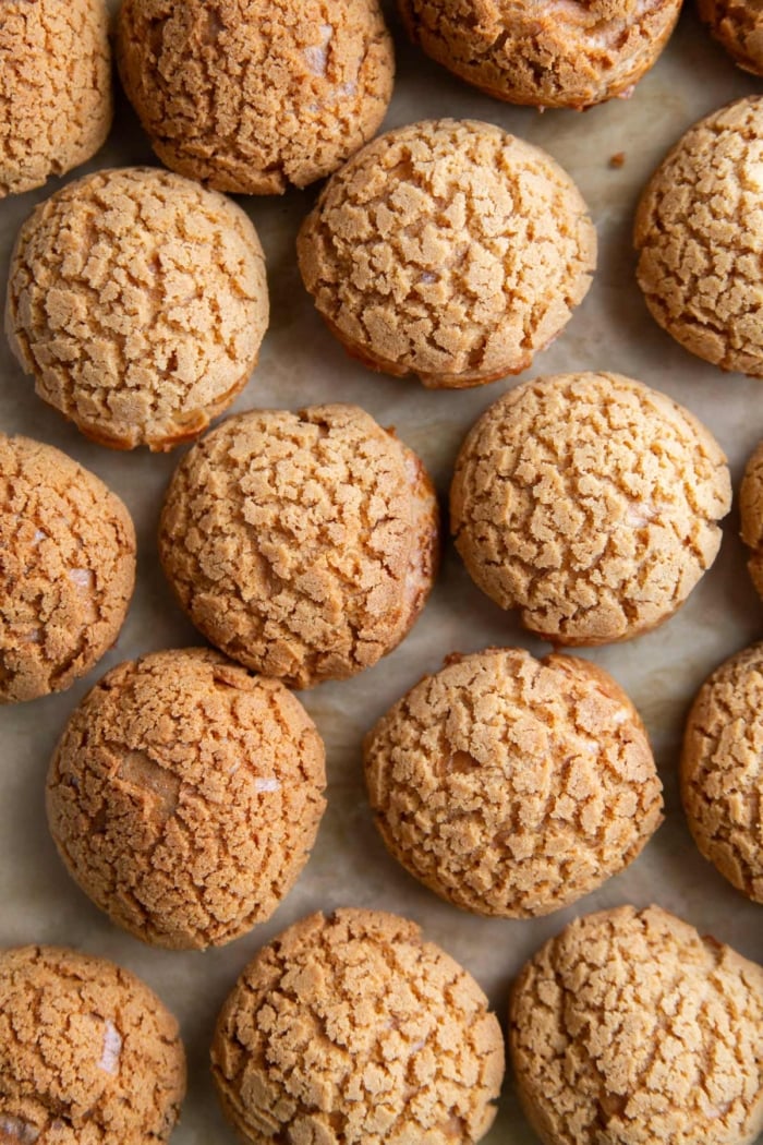 overhead of choux au craquelin arranged on parchment lined sheet tray.