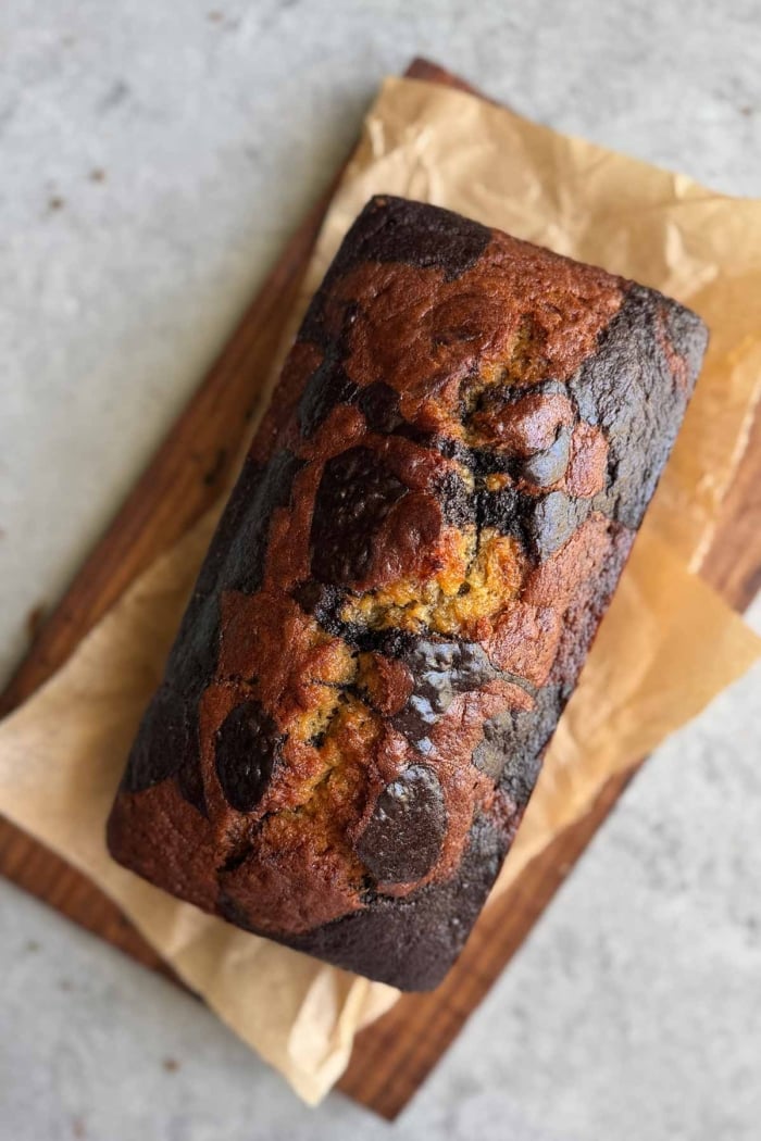 whole loaf of hojicha banana bread on parchment lined wood board.