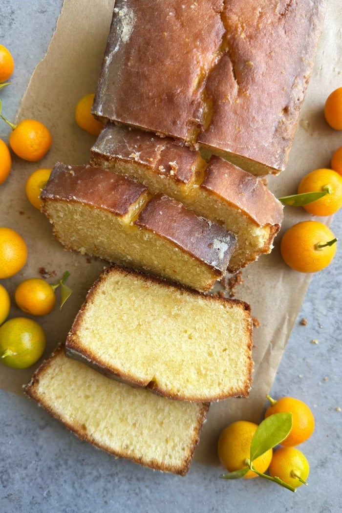 slices of glazed calamansi pound cake surrounded by fresh calamansi fruit.