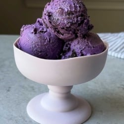 three scoops of ube cookies and cream ice cream in stemmed glass.