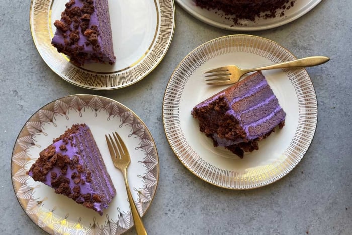 three slices of ube cake on decorative serving plates.