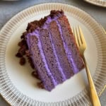 close up sour cream ube layer cake with cake fork on serving plate.