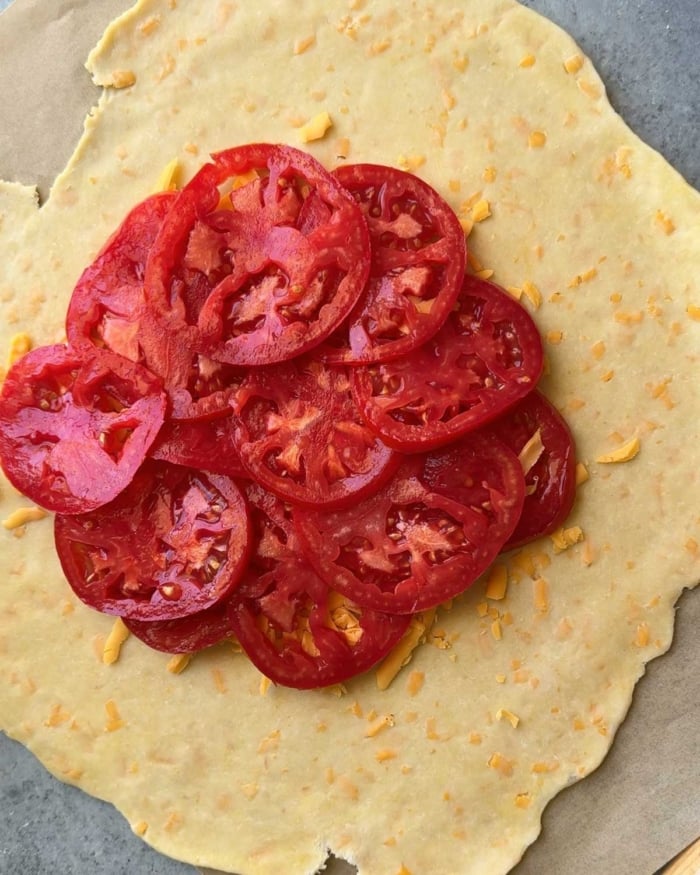 arranged sliced tomatoes over cheese dough.