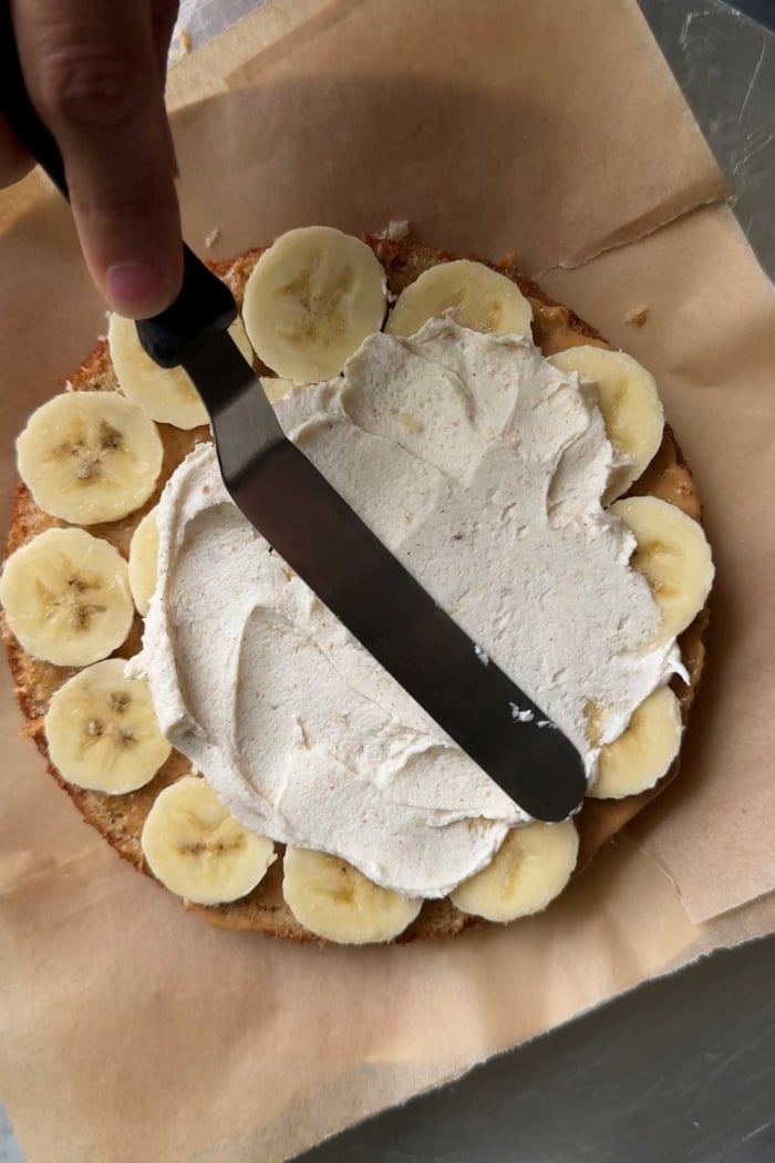sliced bananas being covered with brown butter frosting.