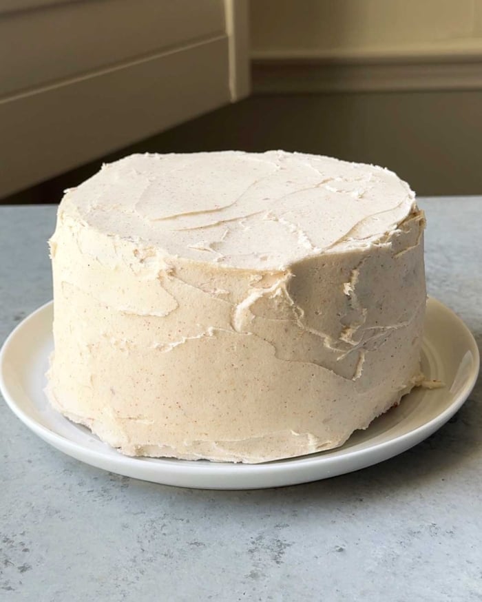 brown butter frosted cake on white serving plate.