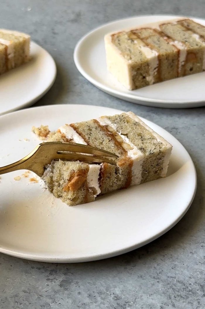 cater or wedding cut of peanut butter banana cake on white plate with gold fork.