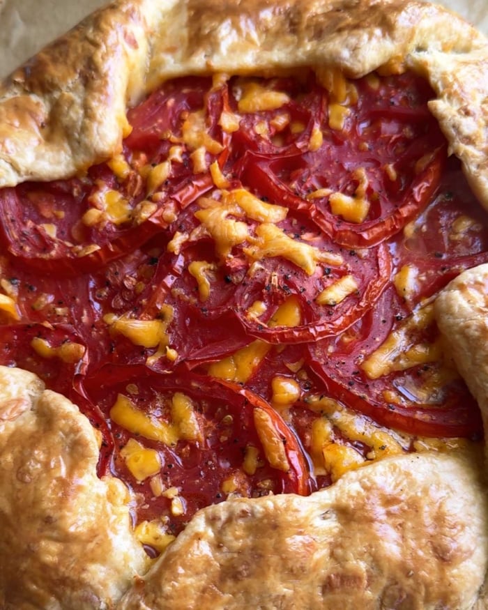 close of baked summer tomatoes with melted cheese in galette.