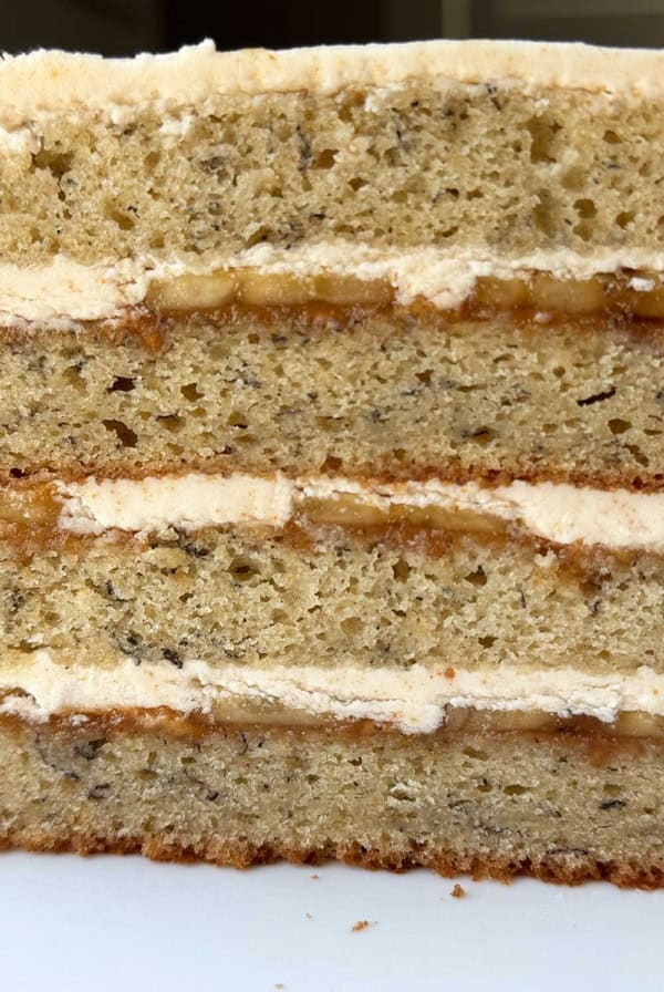 close up interior of banana cake showing brown butter frosting, peanut butter layer, and sliced bananas.