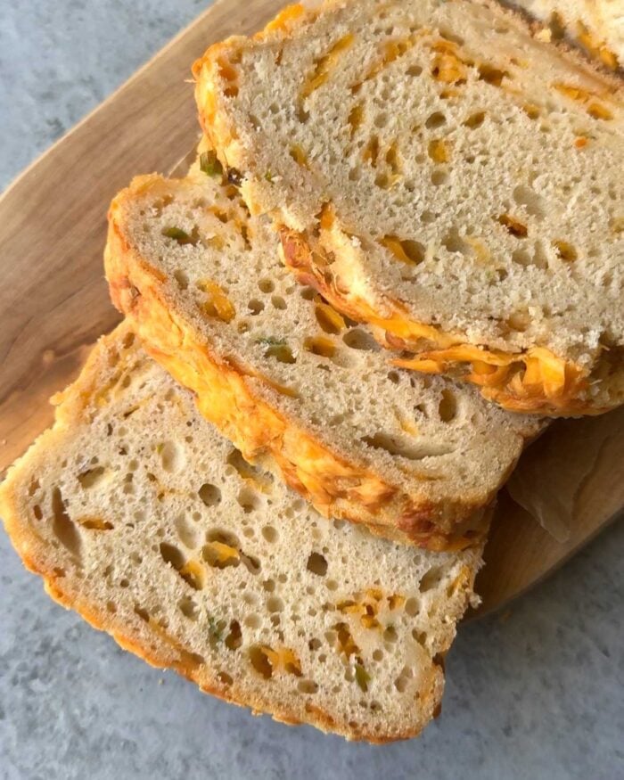 slices of cheddar beer bread on wooden board.