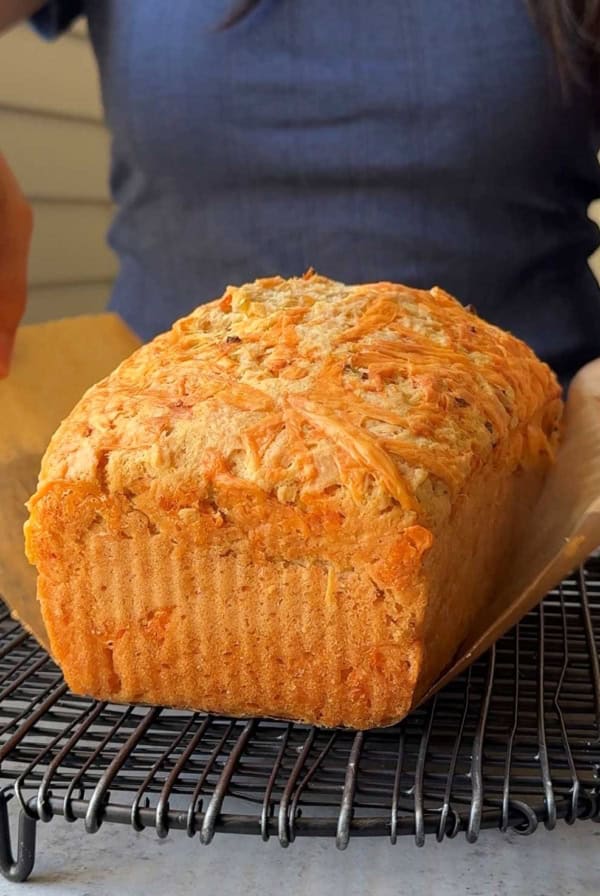 cheddar beer bread placed on black cooling rack.