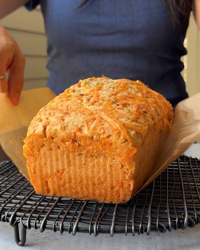 cheddar beer bread placed on black cooling rack.